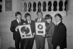 Alan Livingston (centre), president of Capitol Records, and the Beatles display gold records presented to the quartet on 10 February 1964.