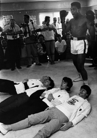 The Beatles, from right to left, Paul McCartney, John Lennon, Ringo Starr, and George Harrison, pretend to be knocked out by a fake blow from Cassius Clay (Muhammad Ali), lying on the floor of the ring, while visiting the heavyweight contender at his training camp in Miami Beach, Florida, USA, Tuesday February 18,1964. (AP Photo)